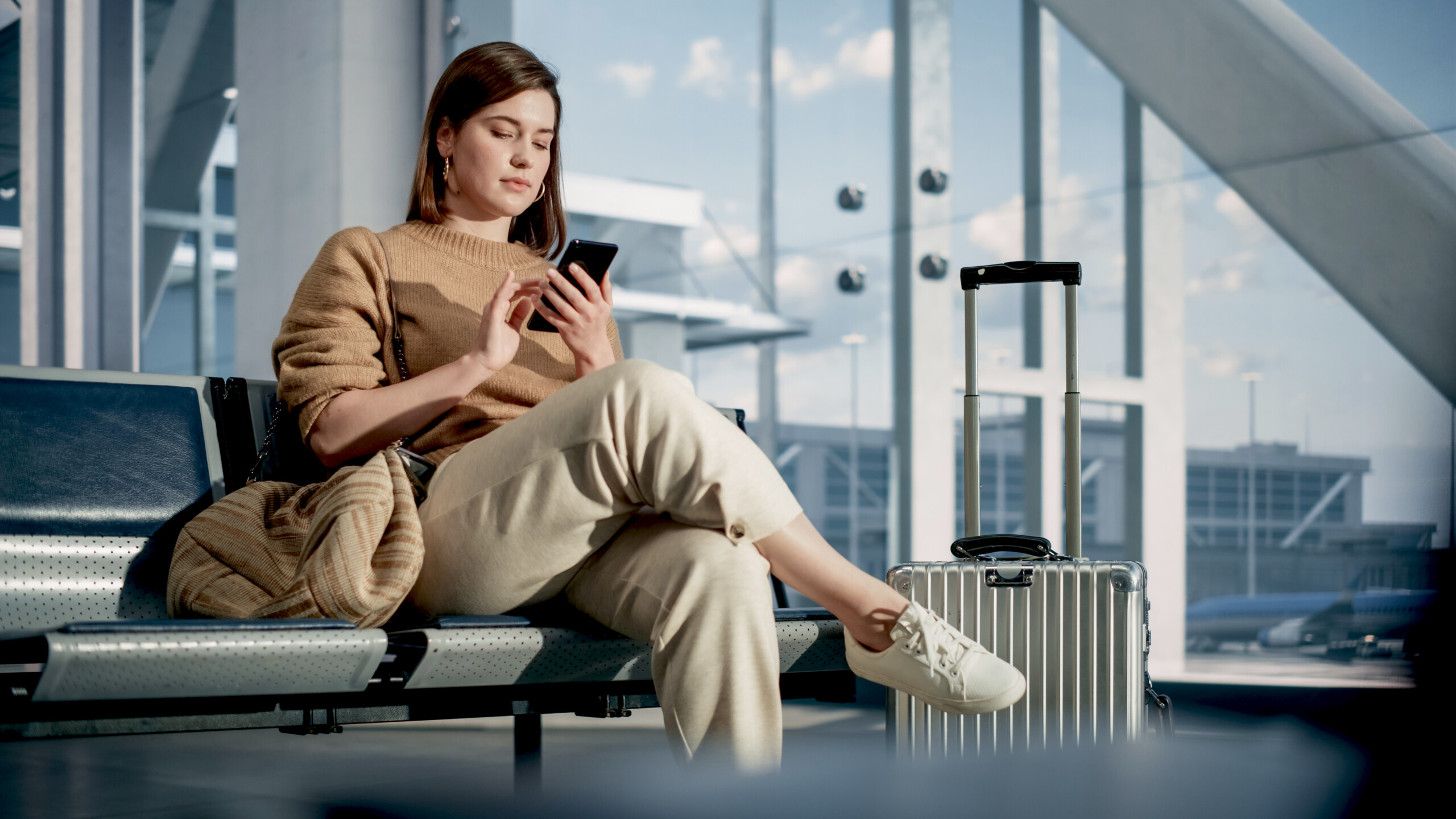 Airport Terminal: Woman Waits for Flight, Uses Smartphone, Brows